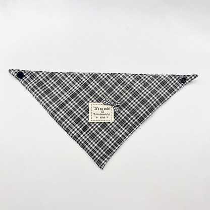 Black Bandana pet neckwear spread flat with white checks, corner snaps and a small bow beside a square label.