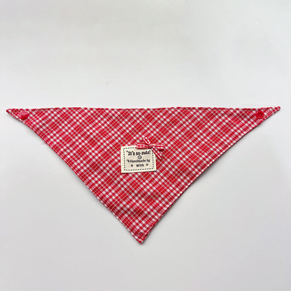Red Bandana pet neckwear spread flat with white checks, corner snaps and a small bow beside a square label.