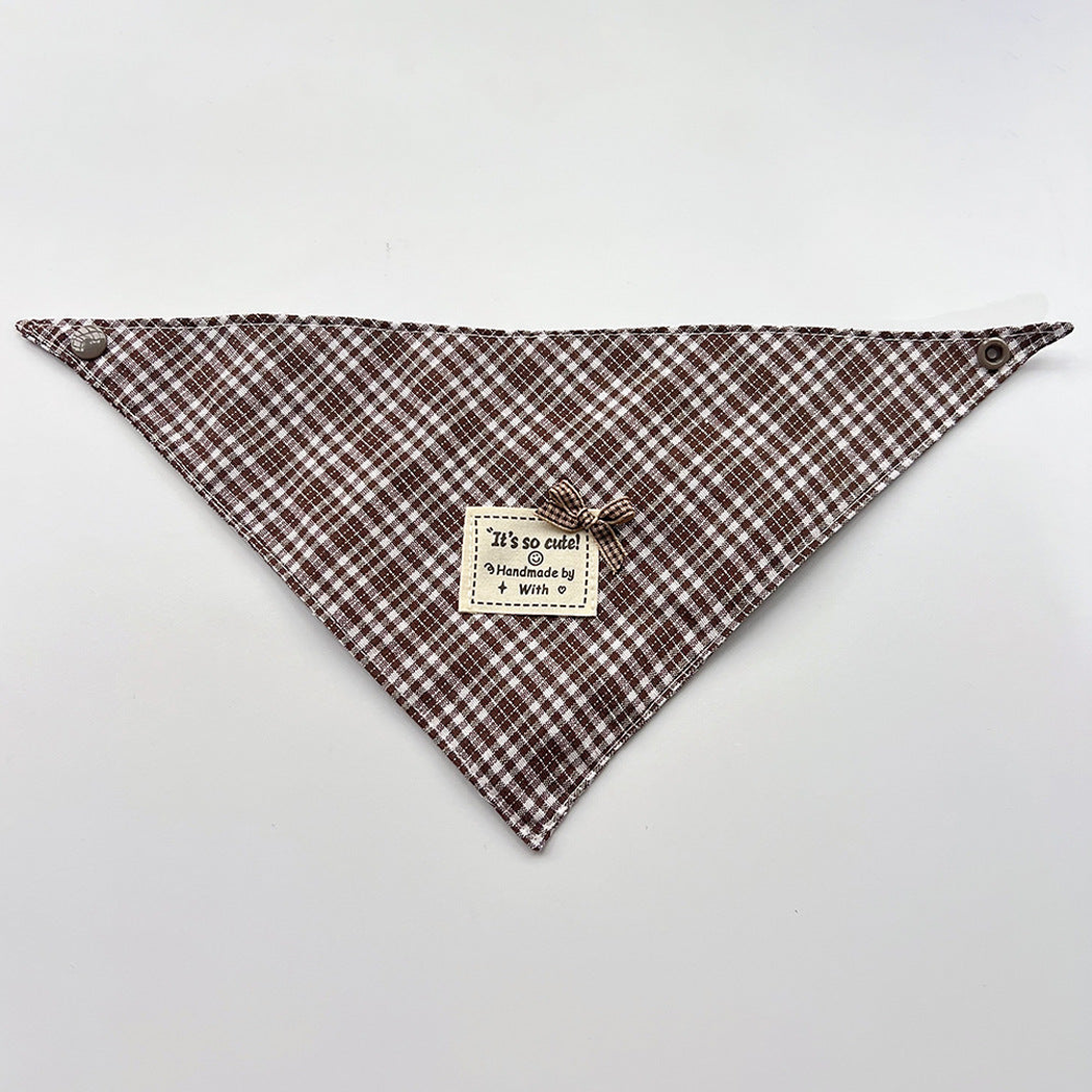 Brown Bandana pet neckwear spread flat with white checks, corner snaps and a small bow beside a square label.