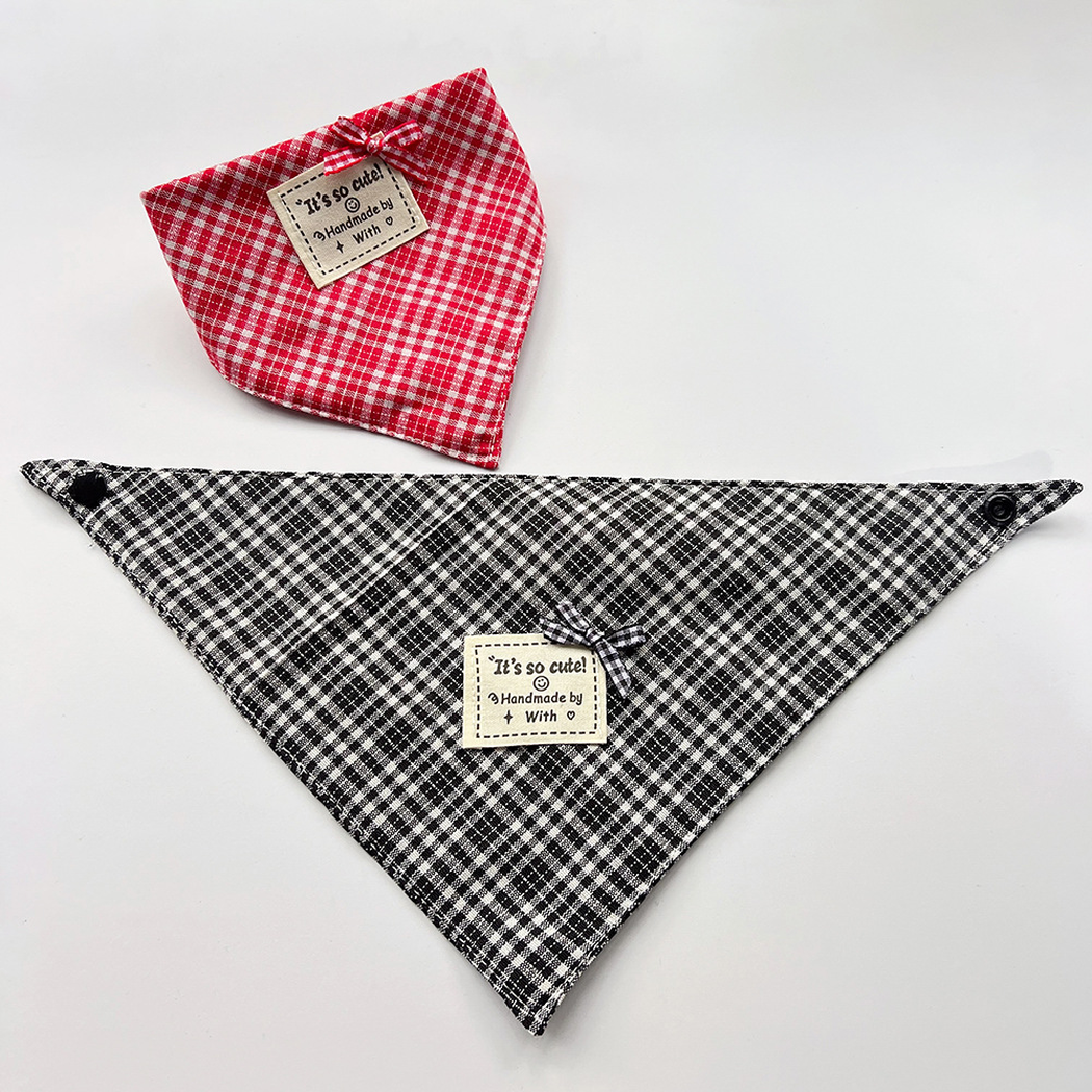Red checked pet neckwear in a curved bandana shape beside black checked pet neckwear spread flat with corner snaps.