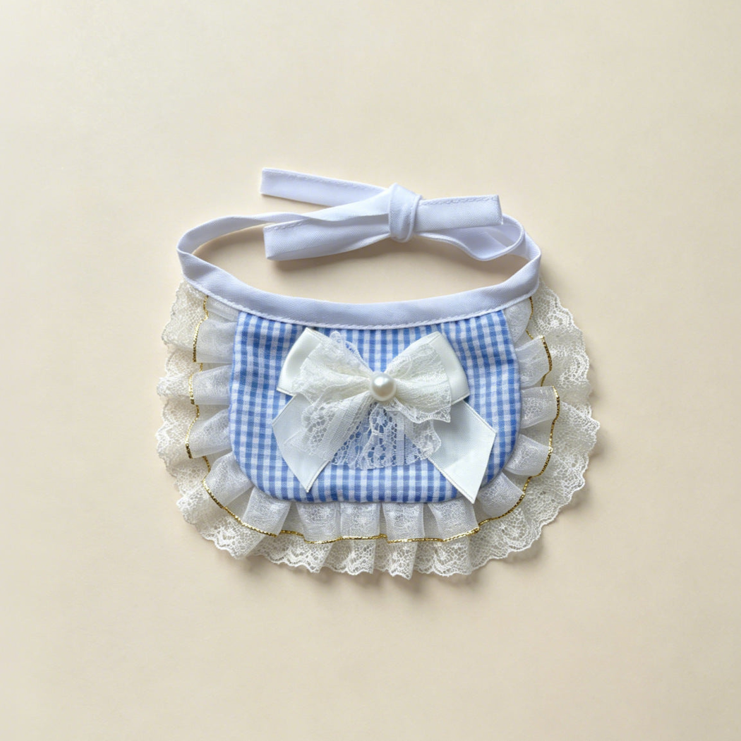 Blue gingham pet neckwear with a white bow, layered ruffles, and white tie straps.