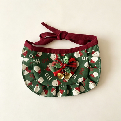 Santa Bib Pet Neckwear with green Santa print, ruffled border, holly-decorated bow and two gold-tone bells.