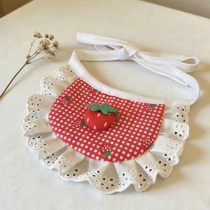 Rounded red gingham pet neckwear with a raised strawberry decoration, white eyelet ruffles, and bow-tied white straps.