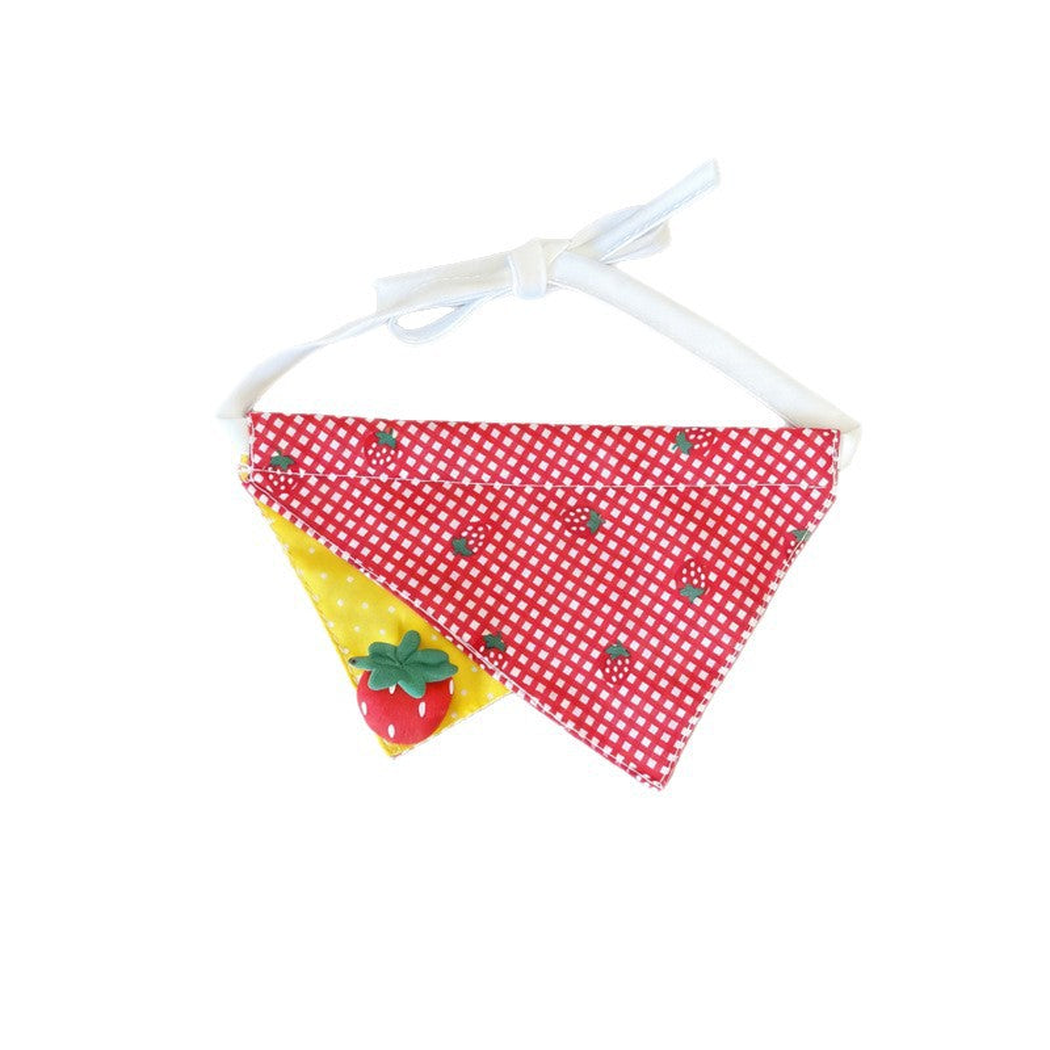 Pet neckwear with overlapping red gingham and yellow dotted triangles, a strawberry decoration, and white ties.