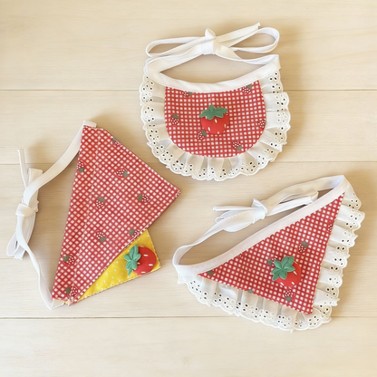 Three strawberry gingham pet neckwear designs arranged together, showing rounded, ruffled triangular, and overlapping panel shapes.