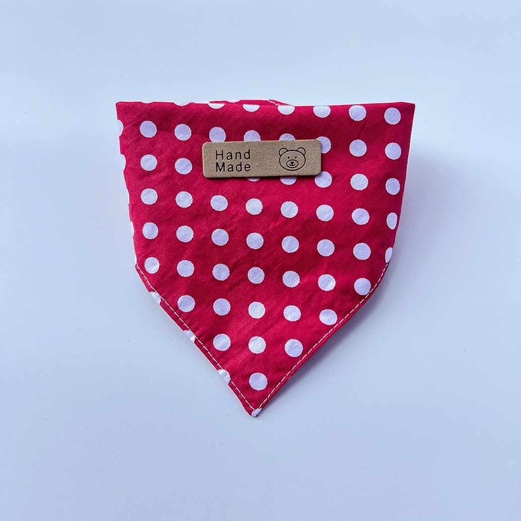 Red pet neckwear with white polka dots folded into a pointed bib shape.