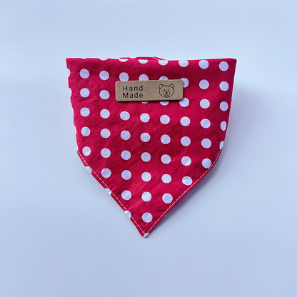 Red pet neckwear with white polka dots folded into a pointed bib shape.