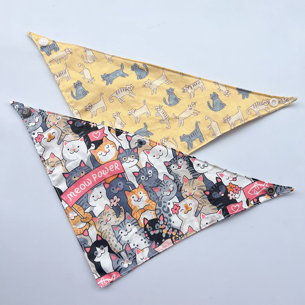 Yellow and multicolor cat-print pet neckwear spread flat with corner snaps visible.