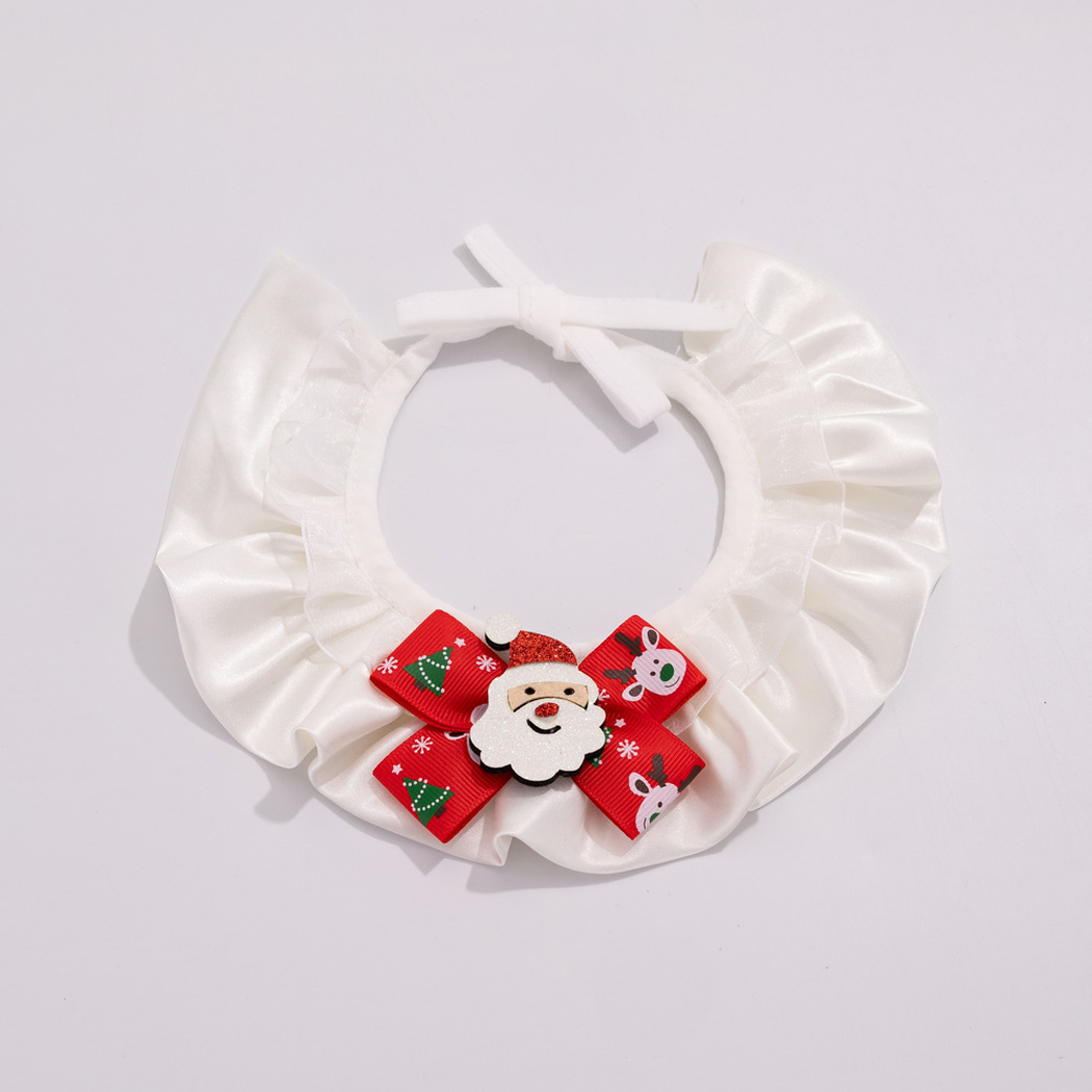 Santa pet neckwear with white layered ruffles, a red patterned bow, and white ties on a pale background.
