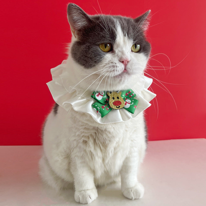 Gray and white cat wearing Reindeer pet neckwear with white ruffles and a green bow.