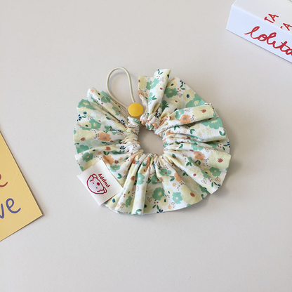 Yellow floral ruffled Pet Neckwear with mint-green and peach flowers and a round yellow disk.