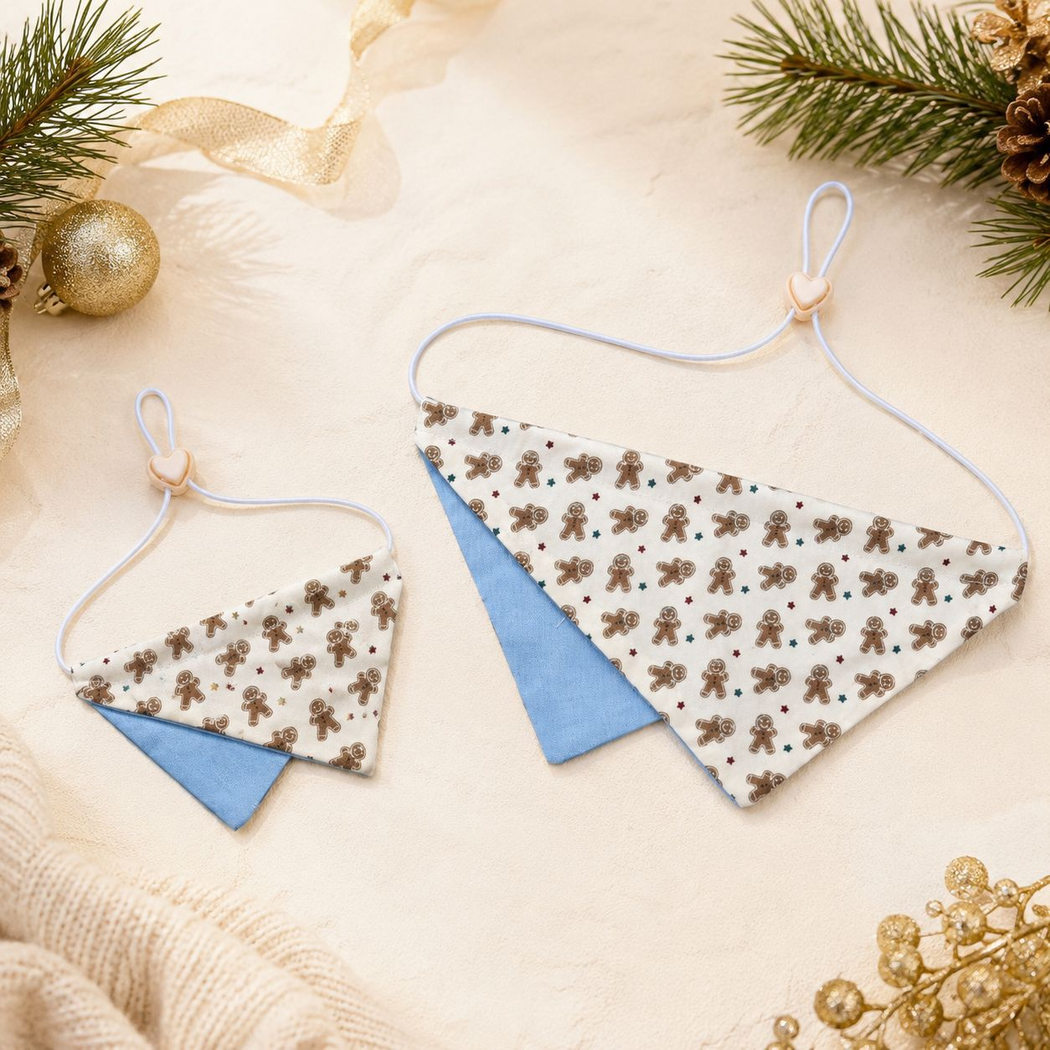 Two Gingerbread-style pet neckwear pieces with blue lower panels on a festive tabletop