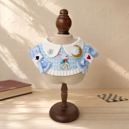 Blue-and-white patterned pet neckwear with bows displayed on a wooden stand against a textured wall