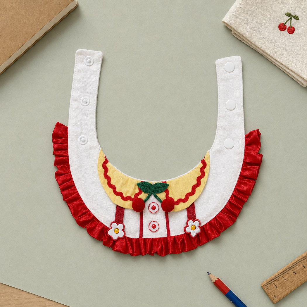 Cherry-themed decorative pet neckwear laid flat, showing its ruffled edge and front details