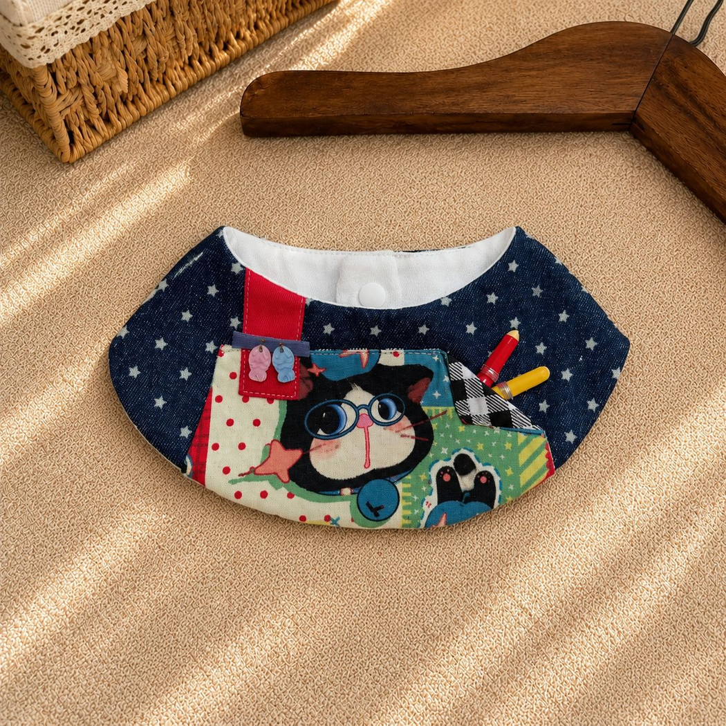 Close view of the pet bib's curved neckline, white edge trim, front pocket, and snap fastener
