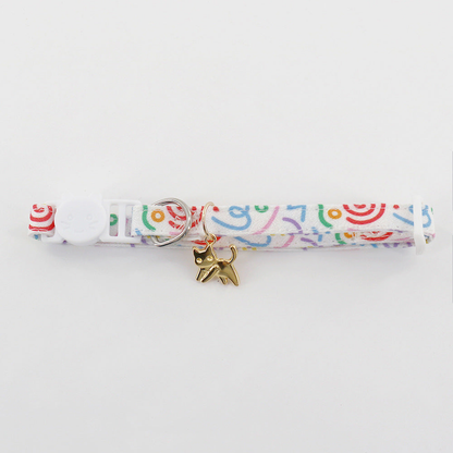 Close-up of white patterned pet neckwear with a gold-tone cat charm