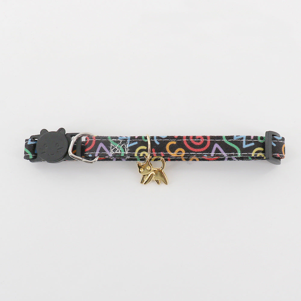 Close-up of black patterned pet neckwear with a gold-tone cat charm