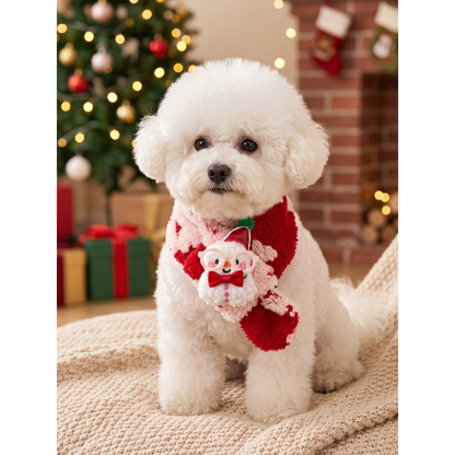 White dog wearing red and pink fuzzy pet neckwear with a snowman decoration in a holiday setting