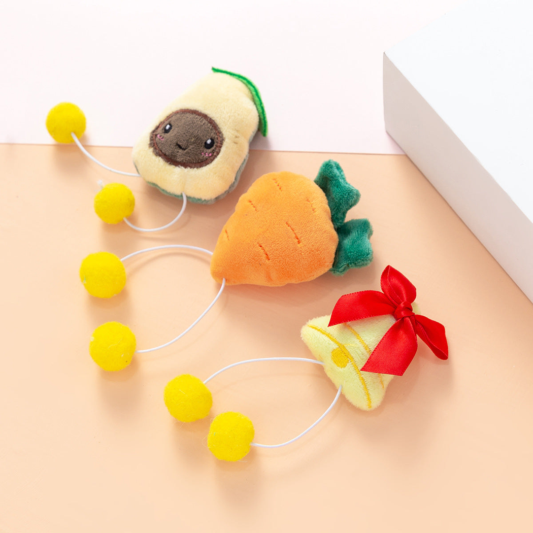 Avocado, carrot, and bell character cat toys arranged on a tabletop