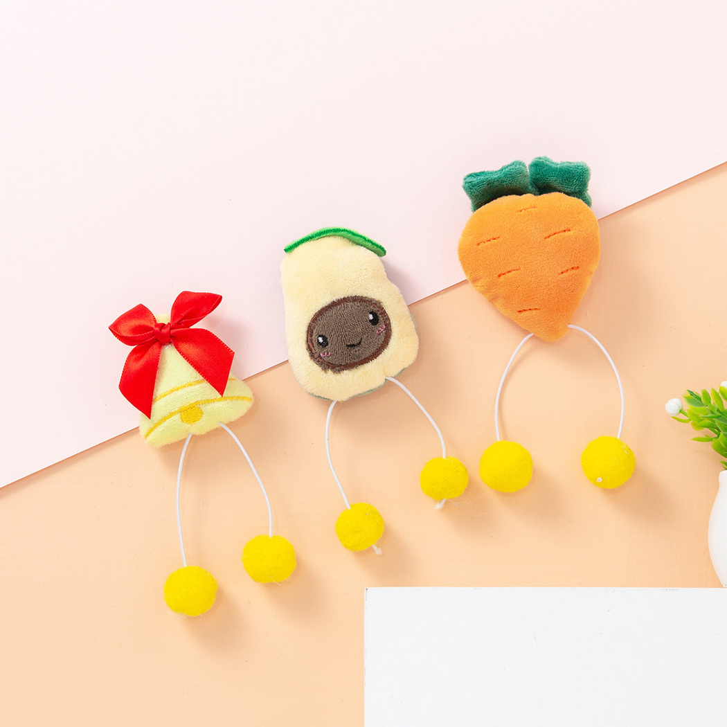 Avocado, carrot, and bell character cat toys arranged on a tabletop
