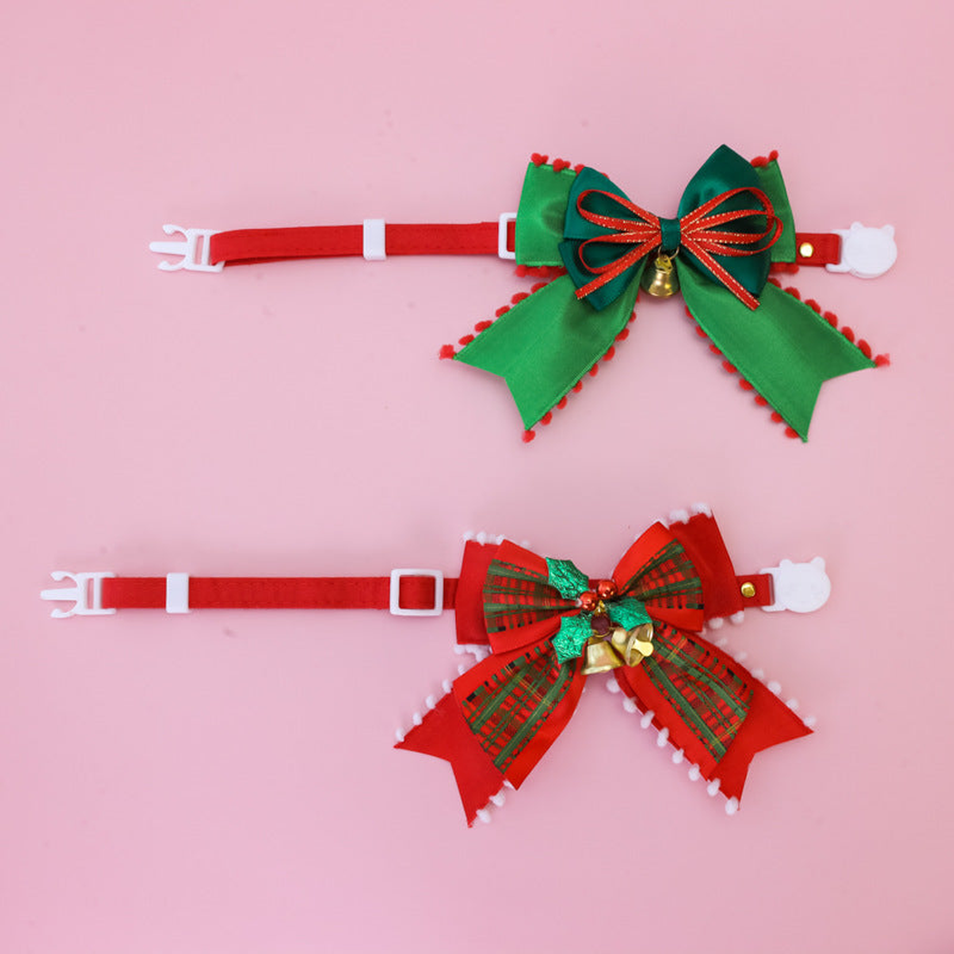 Red and green pet collars with large bows and white buckles displayed flat