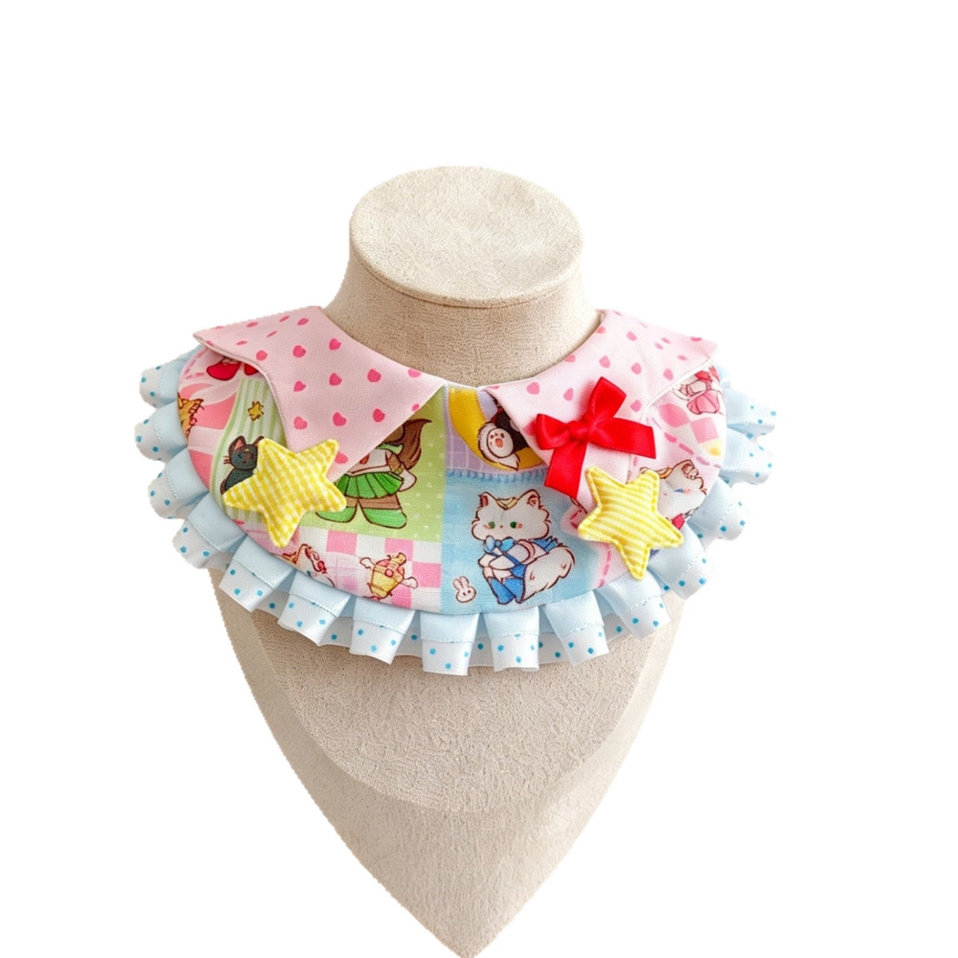 Pastel pet neckwear with an illustrated cat panel, red bow, yellow stars, and blue ruffles