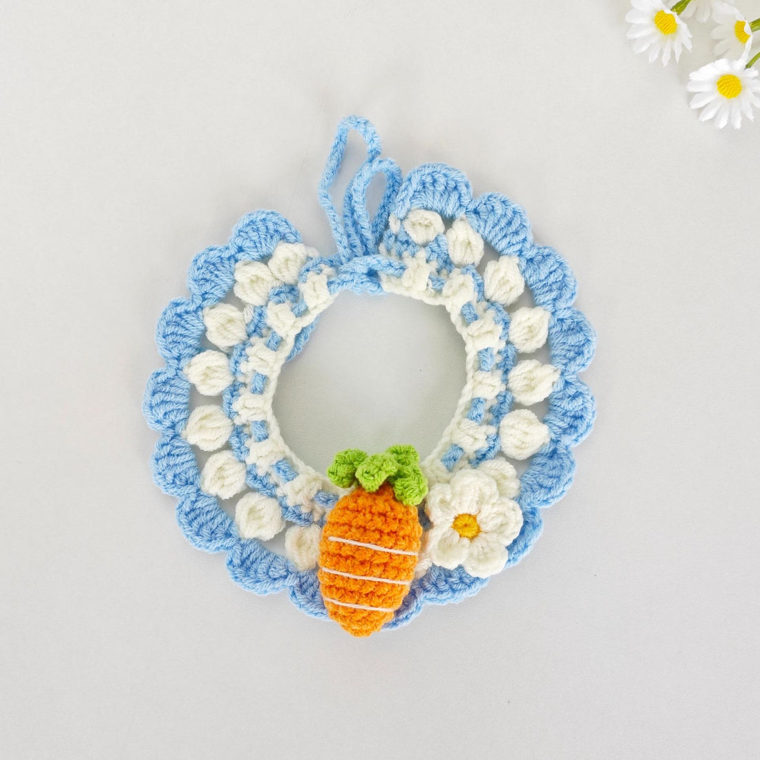Hand holding Mokka crochet carrot cat collar showing texture and carrot charm