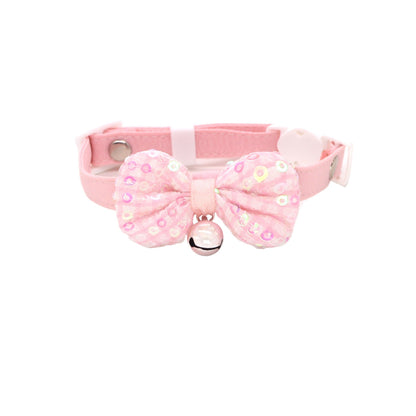 Close-up of pastel bow and bell detail on pink cat collar