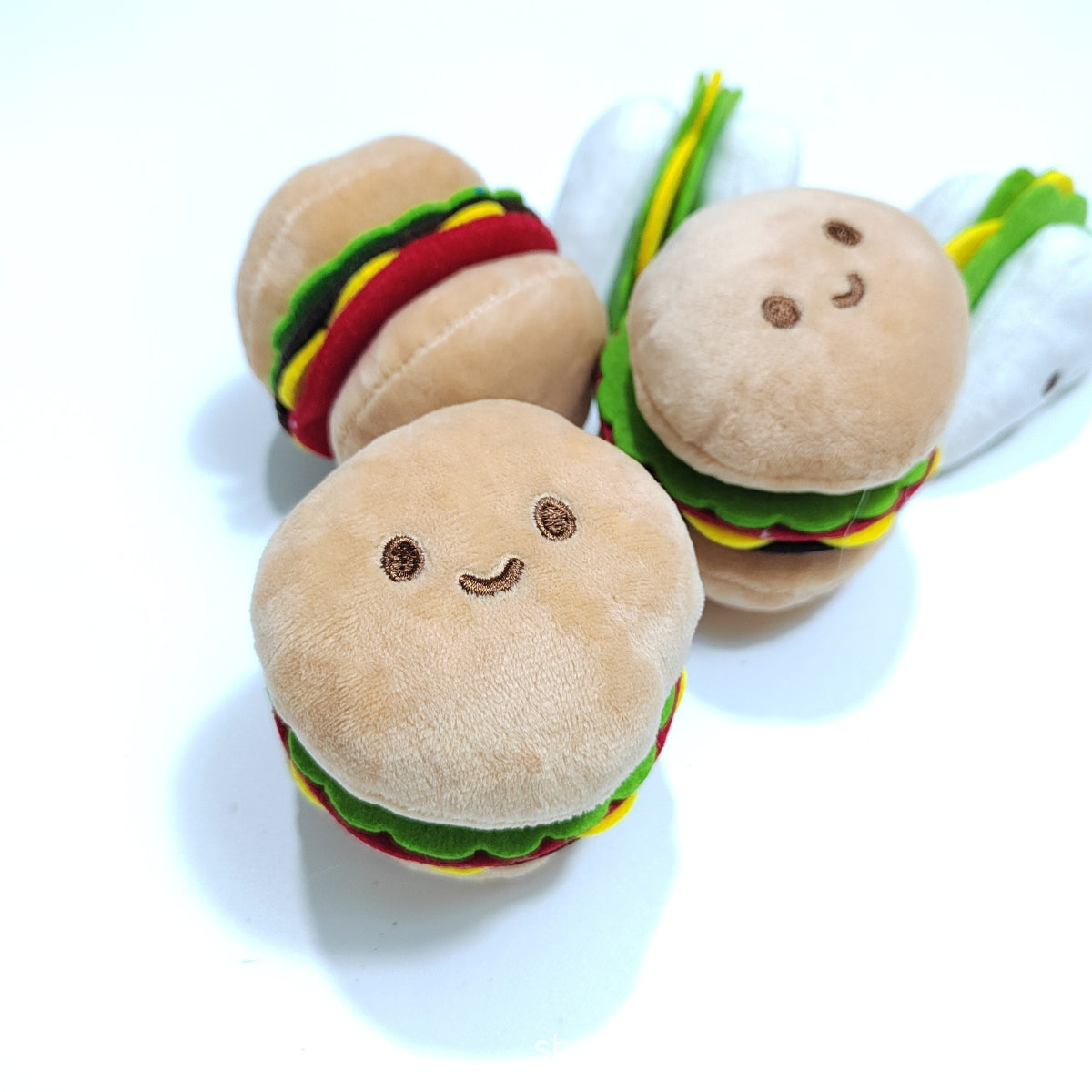 Close-up of Moo plush hamburger cat toy showing soft fabric and embroidered facial features