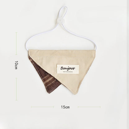 Cat wearing brown ruffle bib sitting on wooden floor